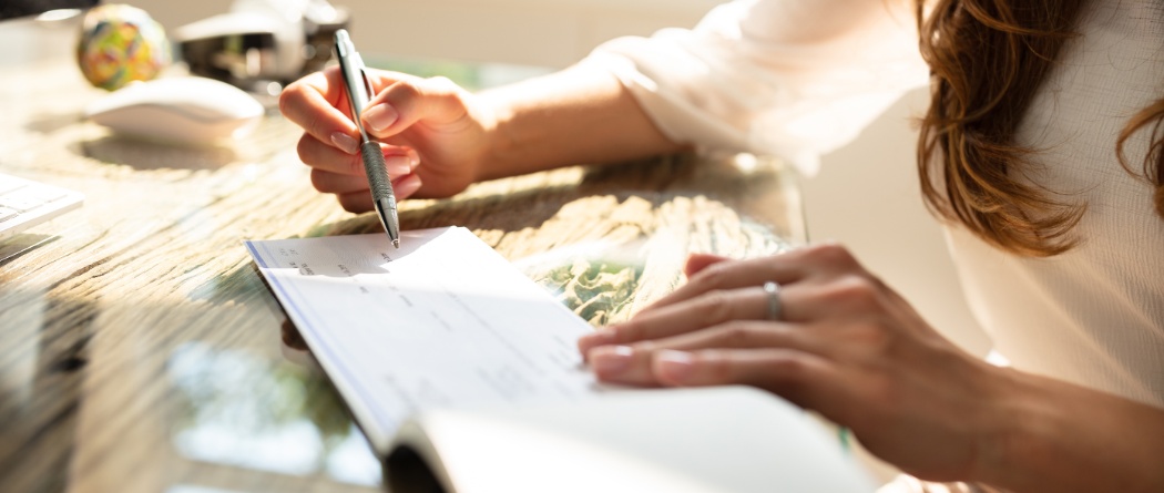 a person writing on a paper business check