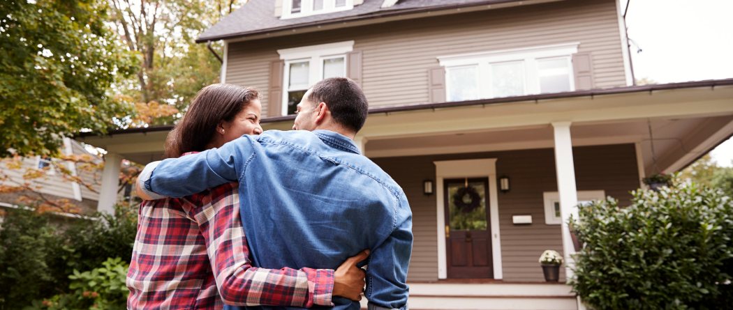 a couple standing in front of their new house