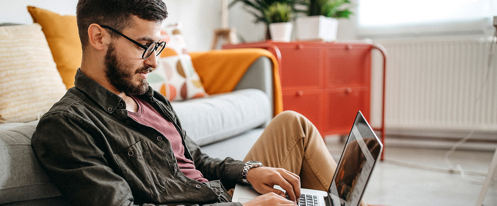 a man sitting on his living room floor working on his laptop